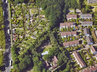 Luftaufnahme eines sehr grünen Stadtgebiets, Häuser, Felder und Straßen sind zu sehen