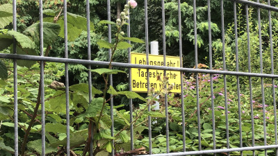Ein Zugang-Verboten-Schild hinter einem Zaun in einem bewaldeten Gebiet