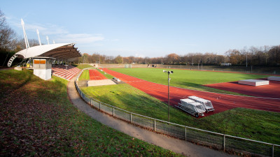 Eine Sportbahn mit Grünfläche, die Tribüne links im Bild